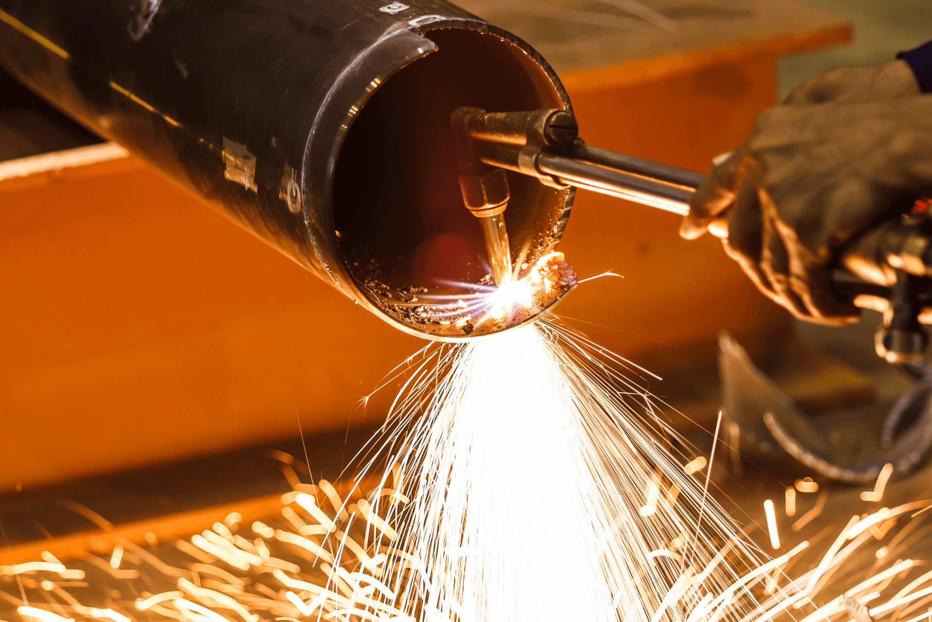 Technician performing metal cutting using Oxy Acetylene flame with equipment supplied by O & T Enterprises, empowering customers in gas application processes.